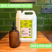 Large white refillable container and brown bottle on a kitchen counter with green tiled wall in the background | Liquipak