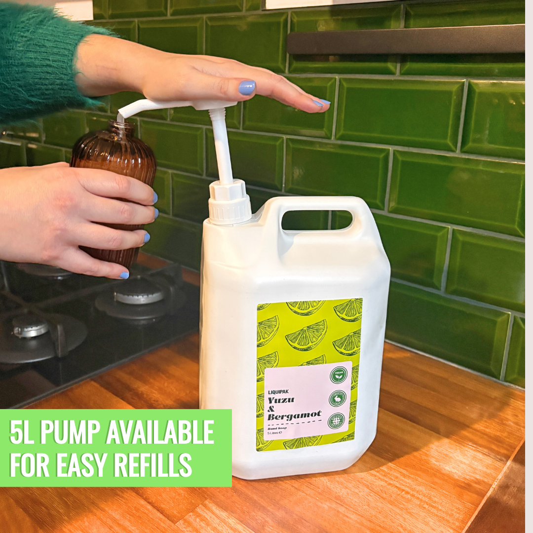 Person using a pump to transfer liquid from a smaller bottle into a larger container with a green label.